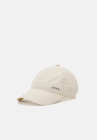Beez värvusega beisballi kork, mis on valmistatud siledast kangast ja millel on kõver äär. Esiküljel on must logo ja kroonil on tikitud detailid.