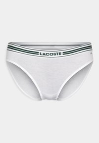 Fehér pamut bugyi zöld és fehér csíkos gumírozott derékkal, középen "Lacoste" logóval. Egyszerű dizájn, puha tapintás.