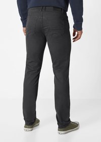 Dunkelgraue Jeans aus Denim im Slim-Fit, mit Gesäßtaschen und einem Etikett am Bund, kombiniert mit olivgrünen Sneakers.