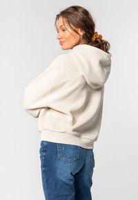Lichtbeige hoodie van zachte stof, met een kangoeroezak en een capuchon met trekkoorden. Gecombineerd met denim jeans, met een relaxte pasvorm.
