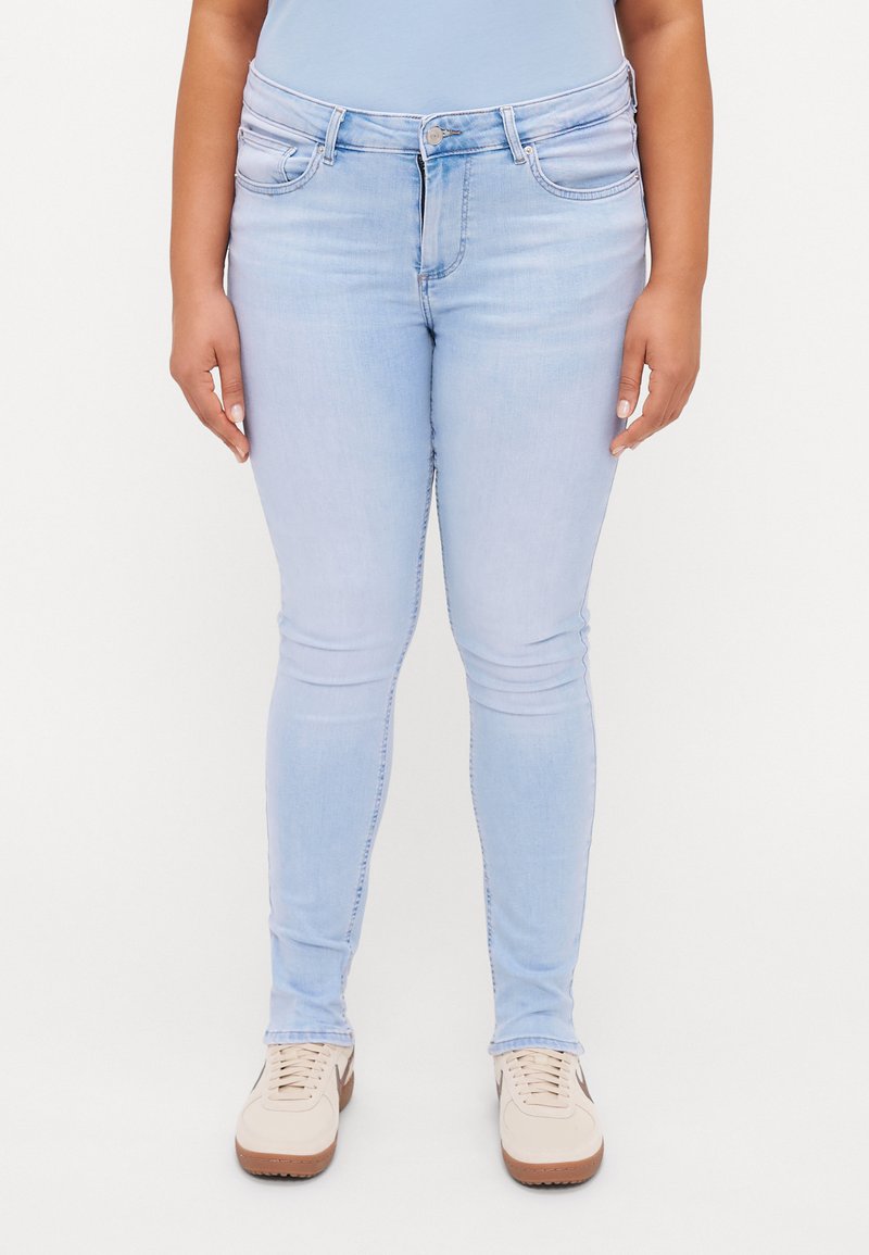 Jeans ajustados de un azul claro, confeccionados en denim con una textura suave, que presentan un diseño clásico de cinco bolsillos y una cintura de altura media.