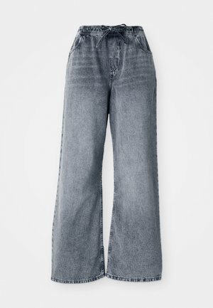 Pantalons en denim large gris avec une taille élastique, une fermeture à cordon, et des poches latérales. Texture décolorée sur l'ensemble du tissu.