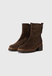 Hnědé semišové kotníkové boty s robustním podpatkem, bočním zipem a poutkem vzadu. Mají minimální šití a odolnou podrážku pro lepší přilnavost.