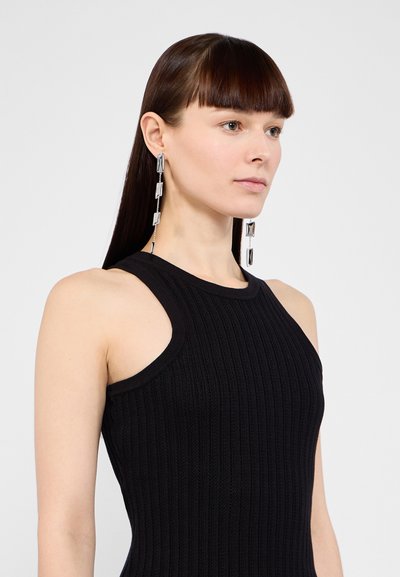 Musthave mustriba mustamata päämeega must kleit. Hõbedased väljapaistvad kõrvarõngad, millel on omavahel ühendatud ristkülikukujulised vormid, lisavad elegantselt aktsenti.