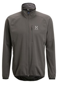Dunkelgraue Softshelljacke mit durchgehendem Reißverschluss, drei Reißverschluss-Taschen, hohem Kragen und weißem Haglöfs-Logo auf der Brust.