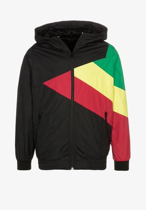Chaqueta negra con capucha con bloques de color rojo, amarillo y verde en diagonal en el pecho y la manga derecha, cremallera frontal y bolsillos con cremallera.