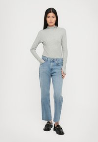 Gray long-sleeve turtleneck top paired with light blue straight-leg jeans and black loafers with gold accents. Simple, casual outfit.
