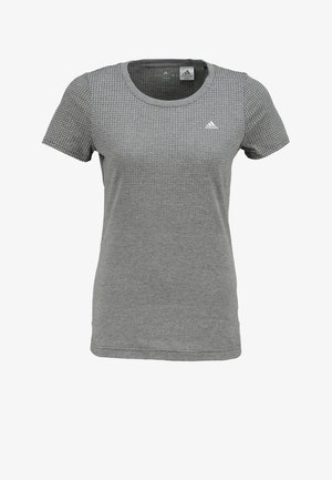 Persona caminando con una camiseta gris de manga corta, leggings capri multicolores con rayas negras y zapatillas deportivas blancas con suelas negras.