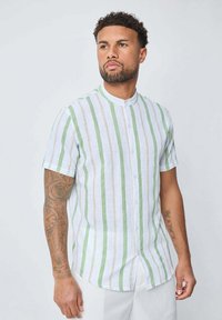 Chemise à manches courtes en lin blanc avec des rayures verticales vertes et beiges, dotée d'un col mao et d'une fermeture à boutons.