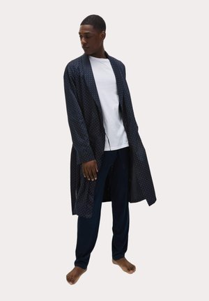 Navyblauer Morgenmantel mit Punkten, langen Ärmeln und offenem Front, getragen über einem weißen T-Shirt und navyblauen Hosen, mit bequemem Schnitt.
