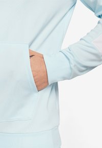 Lichtblauwe hoodie met een kangoeroezak, ribgebreide manchet en een gladde textuur. Het ontwerp heeft een gekleurde accentuering op de mouw.