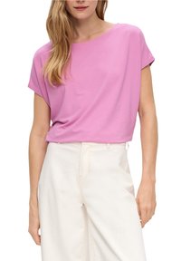 Top rosa a maniche corte con vestibilità rilassata, realizzato in tessuto morbido. Abbinato a pantaloni a gamba larga di colore chiaro, con un design semplice.