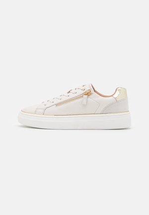 Hvid lavtop sneakers med snørelukning foran, guld lynlås i siden, gulddetaljer på hælen og tyk hvid sål.