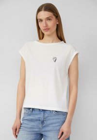 Weißes Baumwoll-T-Shirt mit umgekrempelten kurzen Ärmeln, rundem Ausschnitt und einem kleinen schwarzen Grafikdesign auf der linken Brust. Lässige Passform.