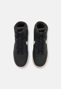 Svart högskurna sneakers med läderöverdel, texturerad detalj, sex snörhål, vit swoosh och rund sula i gummigummi. Fodrad med mörkt tyg.