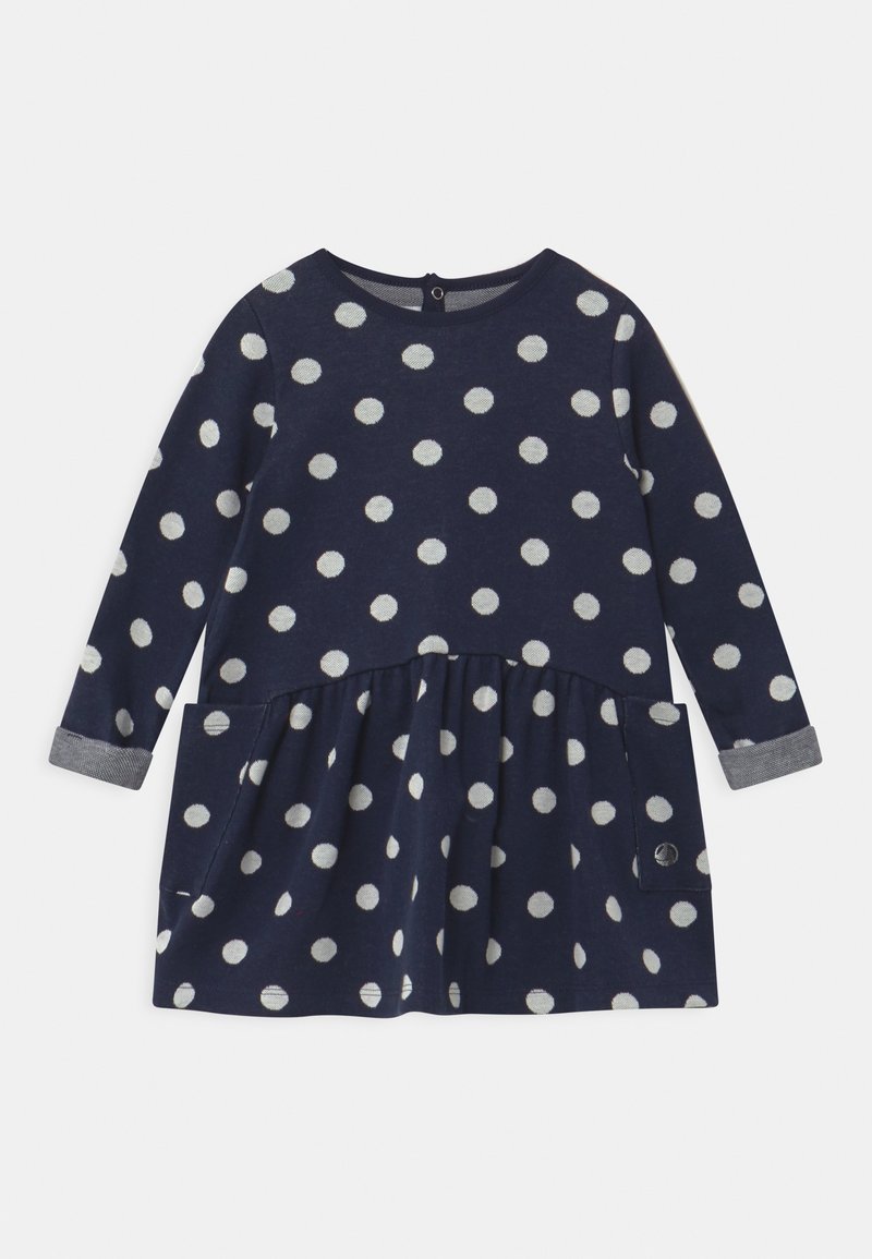 Robe manches longues pour tout-petit bleu marine avec des pois blancs, jupe froncée, poches avant et fermeture par boutons au niveau de l'encolure arrière.