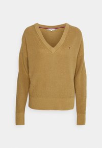 Senfgelbes Strickpullover mit V-Ausschnitt, tiefen Schultern und gerippten Bündchen. Verfügt über ein kleines Logo auf der Brust und einem strukturierten Muster.