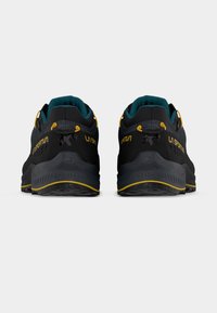 Μαύρα αθλητικά παπούτσια με τυρκουάζ λεπτομέρειες και κίτρινα μεταλλικά στοιχεία. Διαθέτουν υφασμένη, μολυβοειδή σόλα με πολλαπλά προφίλ πέλματος για καλύτερη πρόσφυση.