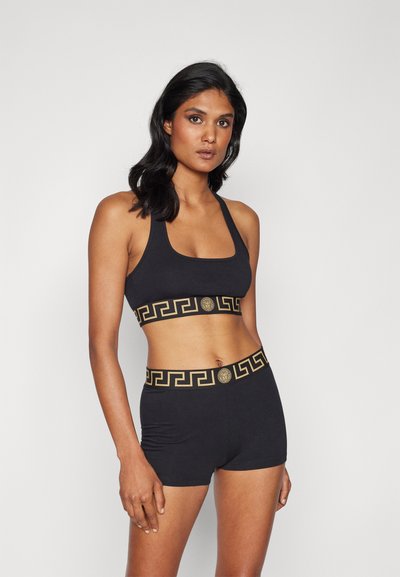 Schwarzes Sport-BH- und Shorts-Set mit einem breiten goldenen griechischen Schlüsselmotiv entlang des Elastikbands. Weicher Stoff, figurbetontes Design, quadratischer Ausschnitt.