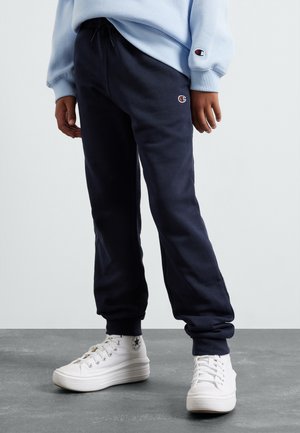 Pantalons de survêtement navy avec des ourlets resserrés, une taille élastique et un patch logo. Assortis à des baskets montantes blanches avec un design texturé.