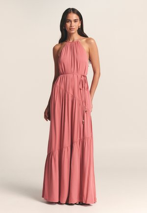 Maximekko pehmeässä persikkapinkissä kankaassa. Saattaa olla halterneck, löysä malli, erilaisella kootulla vyötäröllä ja kerroksellisella röyhelöhelmalla. Sidotaan vyötärölle koristeellisten yksityiskohtien kera.