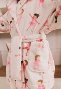 Puha, halvány rózsaszínű polár fürdőköpeny balerinákkal díszítve, átkötős kialakítással, megkötő övvel és elöl praktikus zsebbel.