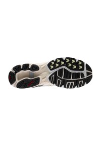 Semelle de sneaker avec un design noir robuste, présentant des crampons proéminents, des accents clairs et une base beige lisse près de la semelle intermédiaire.