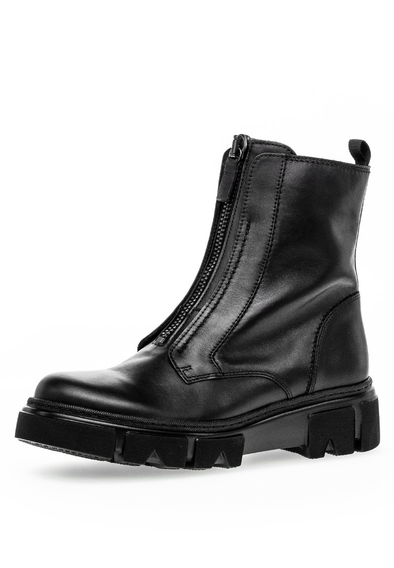 Botte de cheville en cuir noir avec une fermeture éclair sur le côté, semelle en caoutchouc épaisse et motifs de grip prononcés. Finition lisse et détails de couture renforcée.
