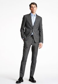 Completo grigio a fantasia con vestibilità slim, abbinato a una camicia dress leggera blu. Scarpa nera completa il look. Design semplice e moderno.