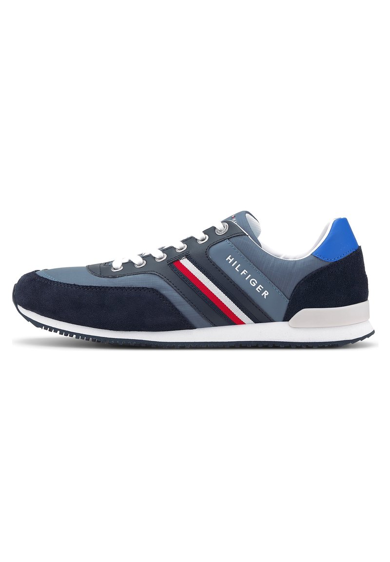 Baskets Tommy Hilfiger bleu marine et grises avec lacets blancs, bandes latérales rouges, blanches et bleu marine, et accent bleu au talon.