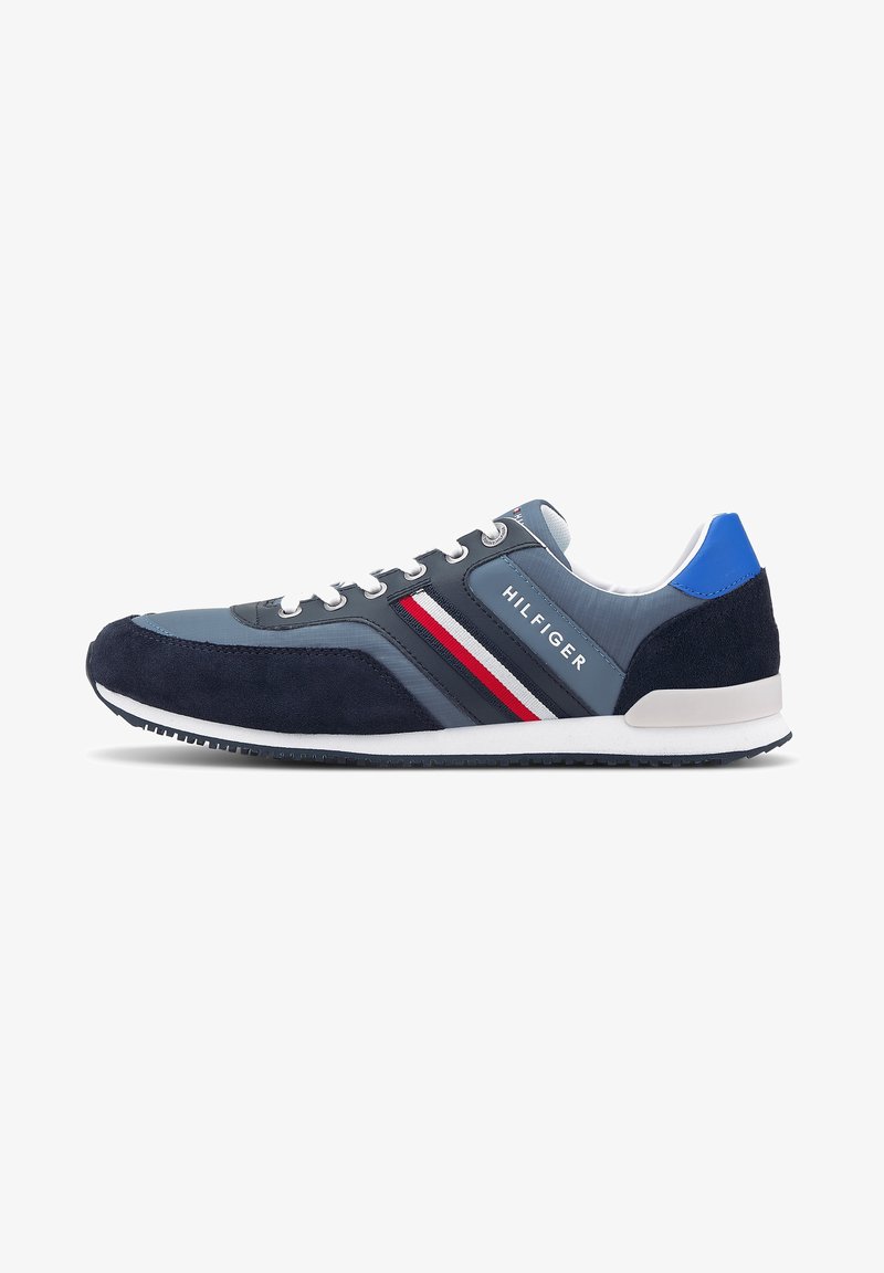 Baskets Tommy Hilfiger bleu marine et grises avec lacets blancs, bandes latérales rouges, blanches et bleu marine, et accent bleu au talon.