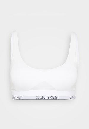 Hvit bralette med brede stropper, rund halslinning og et hvitt bånd med "Calvin Klein"-tekst i svart. Glatt tekstur og minimal design.
