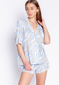 Lett, mønstret pyjamas-sæt med en løs passende kortærmet skjorte og shorts. Farverne inkluderer blå, gul og hvid med prikker.
