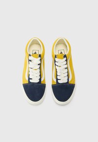 Yellow canvas sneakers with navy suede accents, white laces, and a white side strip. Rounded toe and contrasting stitching detail.