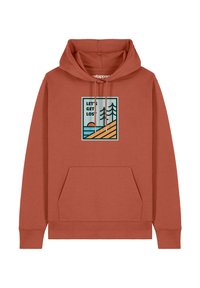 Haut à capuche couleur rouille avec une poche avant et des cordons de serrage. Présente une impression graphique d'arbres et d'un coucher de soleil avec le texte "PERDONS-NOUS".