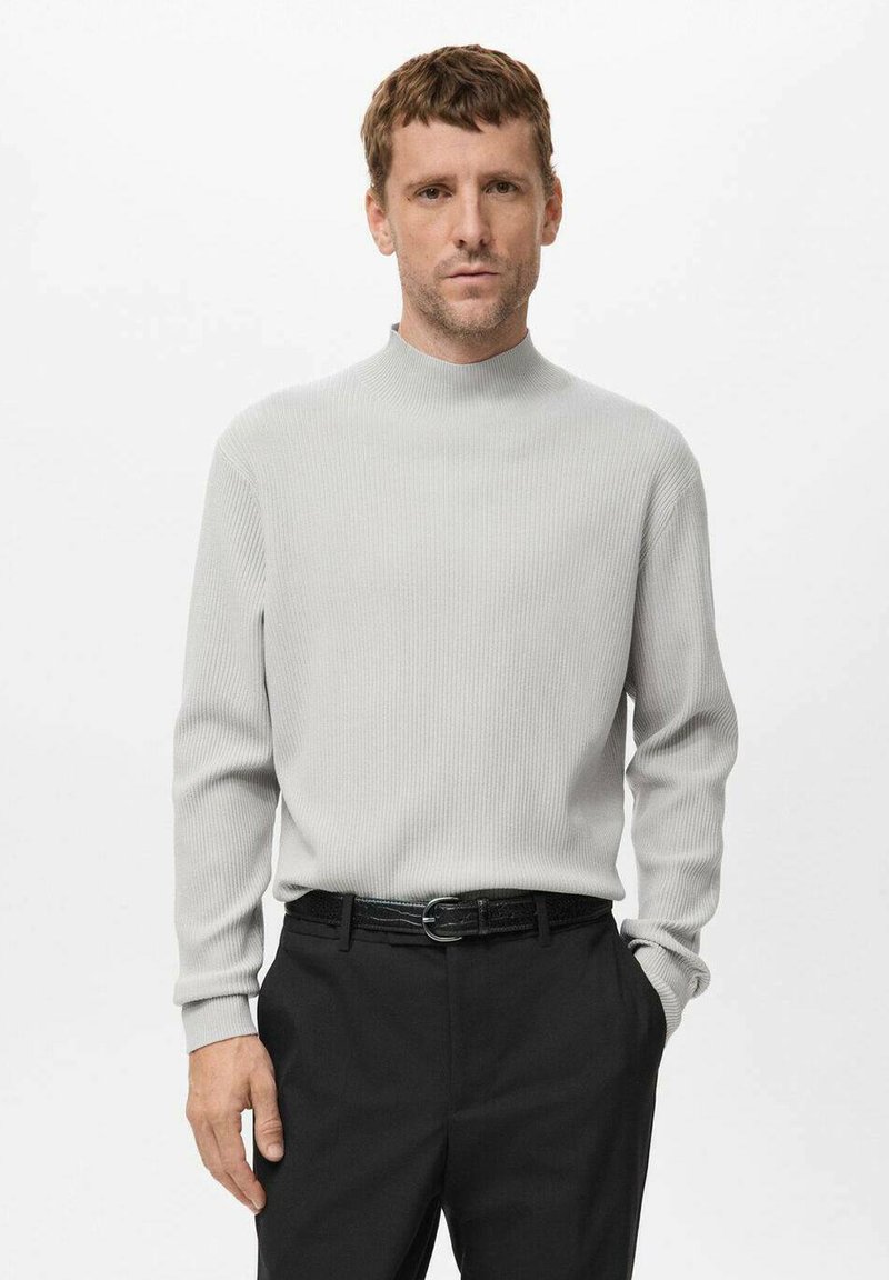 Suéter de tubo de punto acanalado gris claro con mangas largas, combinado con pantalones negros y un cinturón oscuro. Diseño simple y texturizado.