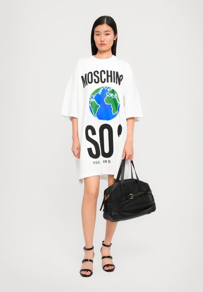 Weißes, übergroßes T-Shirt-Kleid mit einem blauen und grünen Globusdruck, fettem schwarzen Text "MOSCHINO SOS" und einer schwarzen Handtasche mit Riemendetails.