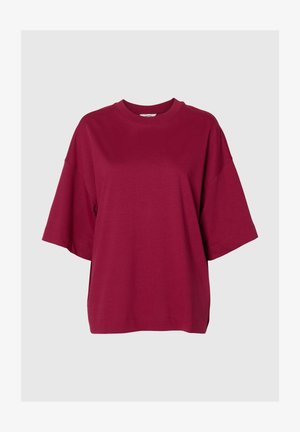Løs passform, kortermet T-skjorte med rund hals i ensfarget burgunder på ensfarget lys grå bakgrunn.