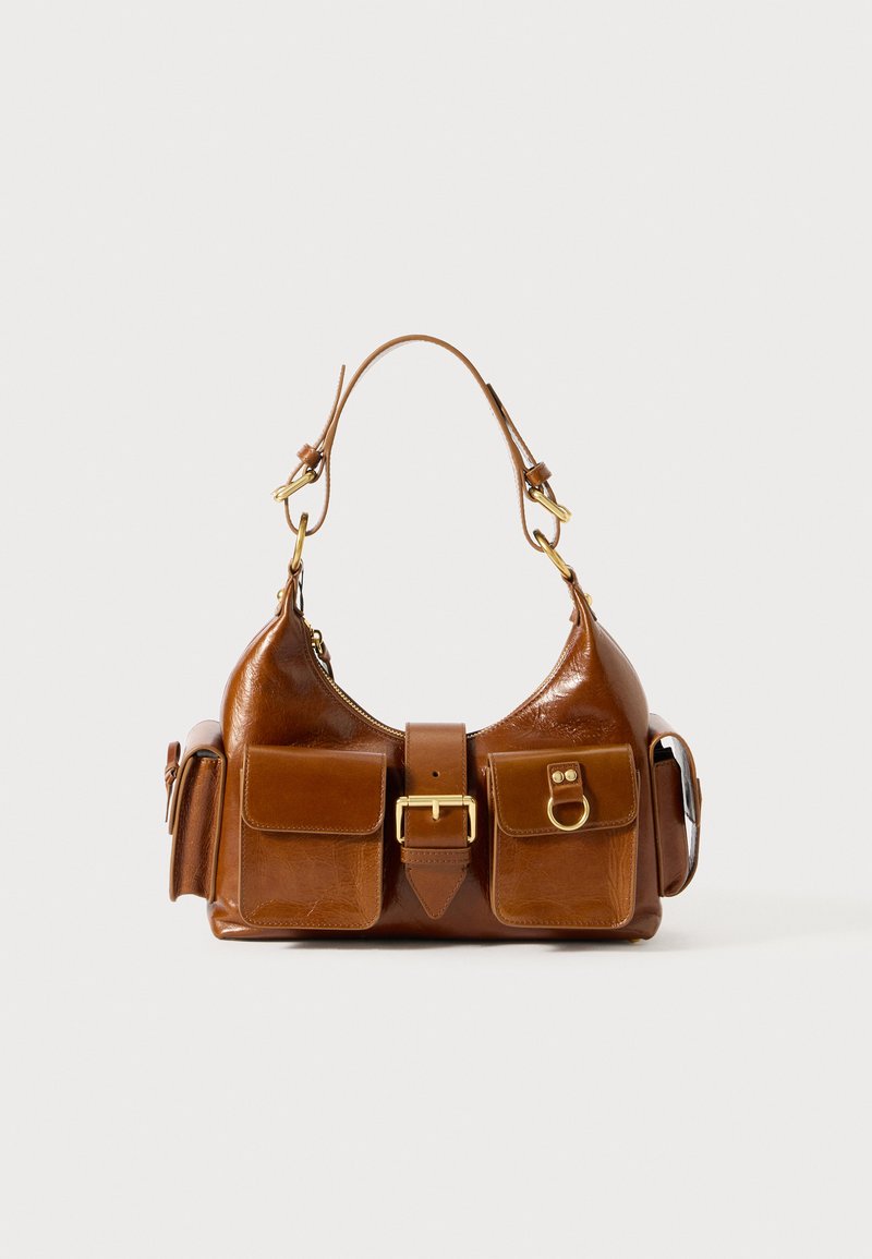 Mala de mão em couro castanho com formato curvo, com acessórios em tom dourado duplo, dois bolsos frontais e uma alça larga. Textura suave com um acabamento elegante.