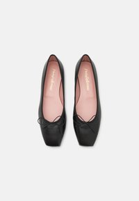 Schwarze Leder-Ballettschuhe mit einem quadratischen Zehenbereich, ausgestattet mit einer pinken Innensohle und einem kleinen Schleifendetail an der Vorderseite. Insgesamt glatte Textur.