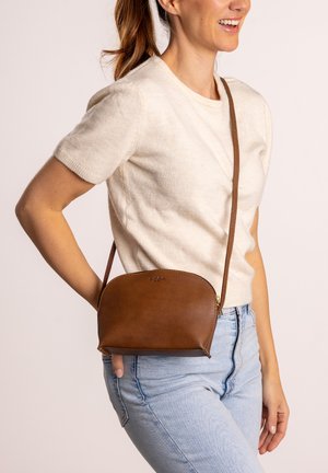 Braune Leder-Umhängetasche mit geschwungener Form, Reißverschluss und dünnem, verstellbarem Riemen. Glatte Textur mit minimalistischem Design.