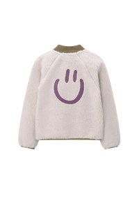Crème-kleurige fleece jas met geribde kraag en manchetten, met een grote paarse glimlachende gezicht op de achterkant.