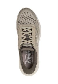 Zapatilla deportiva beige claro con parte superior de malla, puntera redondeada y cordones planos. Presenta la marca "Skechers Air-Cooled" en la plantilla.