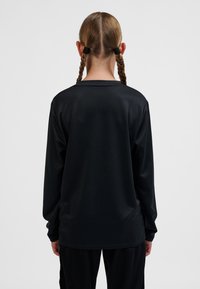 Top negro de manga larga hecho de tela lisa, con escote redondo y corte holgado, sin logotipos ni patrones visibles.