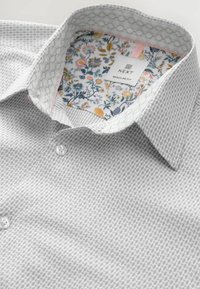 Szürke mintás ing fehér és virágos kontrasztos belső gallérral. Normál szabású, gombos záródású, és texturált szövött anyagból készült.