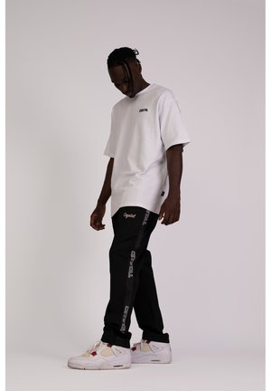 HEAVY SIGNATURE - Tracksuit bottoms - black