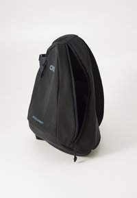 Svart ryggsäck i strukturerad tyg med en dragkedjeförsedd öppning. Anmärkningsvärd logotyp i blått på sidan. Ergonomisk design för komfort.