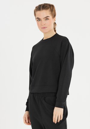 Svart sweatshirts med en avslappnad passform, raglanärmar, ribbade mudd och fåll. Mjuk textur, minimalistisk design, lämplig för vardagsbruk.