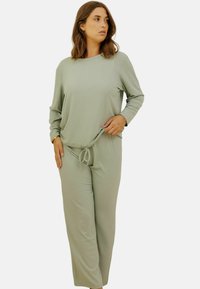 Ensemble de loungewear à rayures vert clair comprenant un haut à manches longues et un pantalon à cordon, présentant une coupe décontractée et une texture douce.