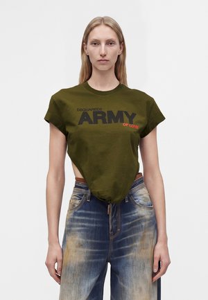 Donna che indossa una maglietta verde oliva con testo "DSQUARED2 ARMY OF LOVE" e jeans blu scoloriti a vita alta su sfondo bianco semplice.